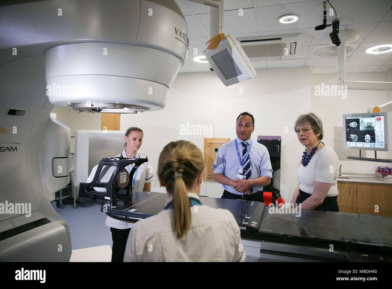 Prime Minister Theresa May (right) is shown the advanced radiotherapy system during her visit to Addenbrooke's Hospital in Cambridge, where she announced new research and funding for prostate cancer treatment, and met NHS staff to discuss the challenges they face as the Government prepares to bring forward a long-term plan for the health service. Stock Photo