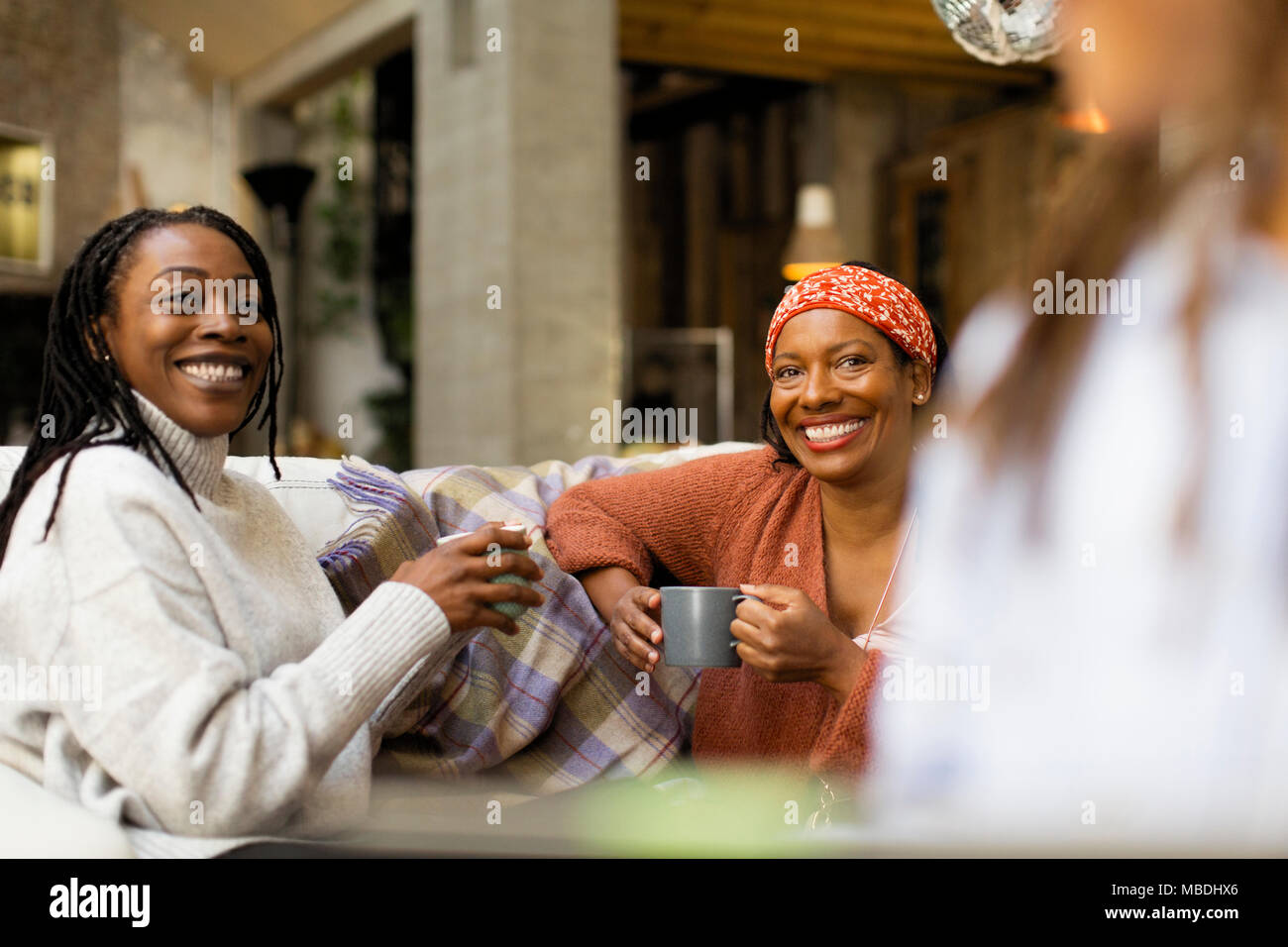 Smiling women talking and drinking coffee on sofa Stock Photo