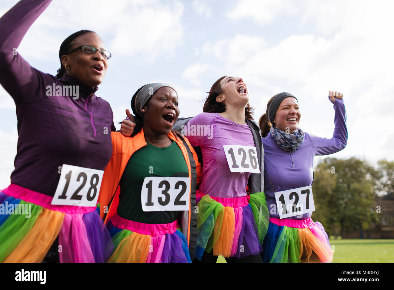 Enthusiastic female runner friends in tutus cheering at charity run Stock Photo