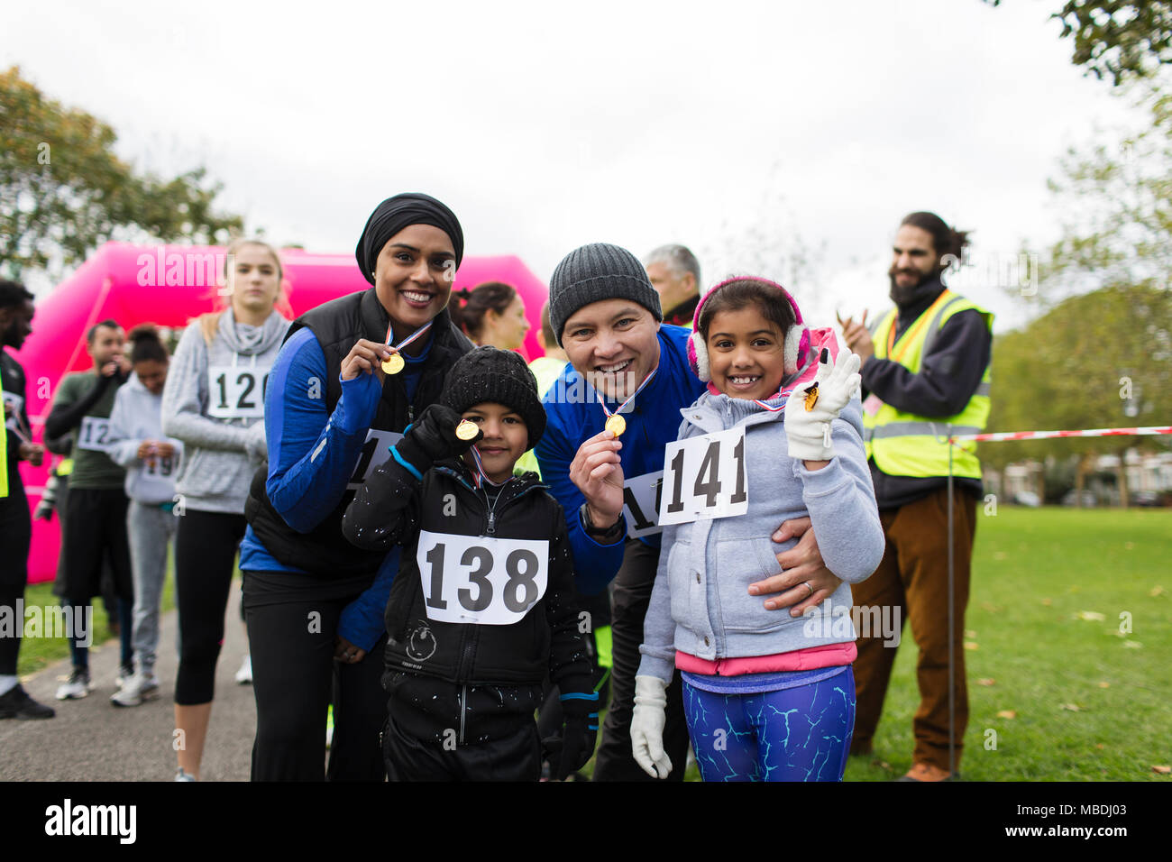 Portrait confident family showing medals at charity run in park Stock Photo