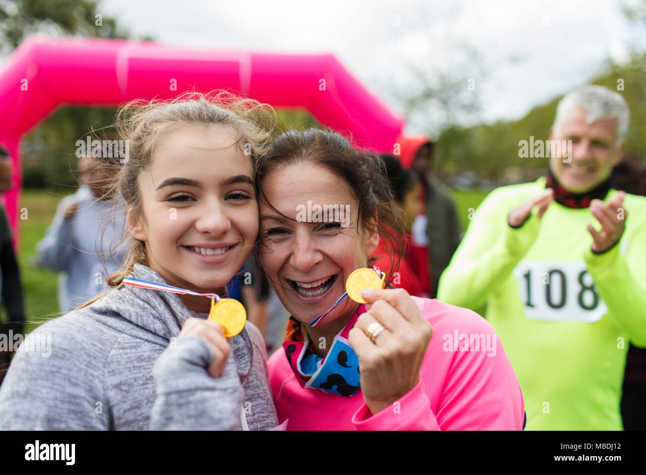 Portrait smiling, confident mother and daughter runners showing medals at charity run Stock Photo