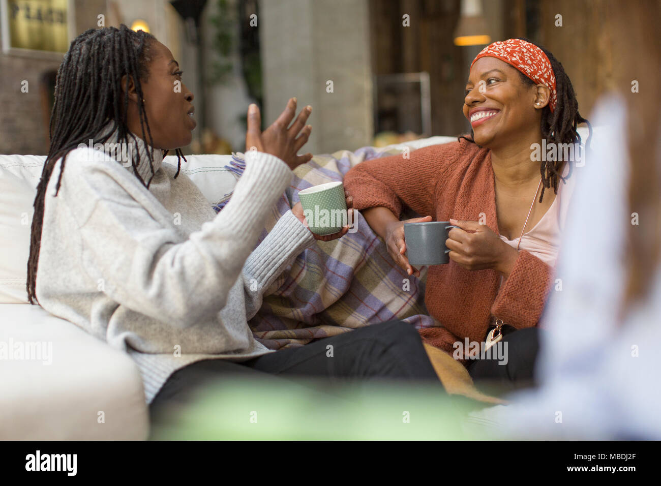 Women talking and drinking coffee on sofa Stock Photo