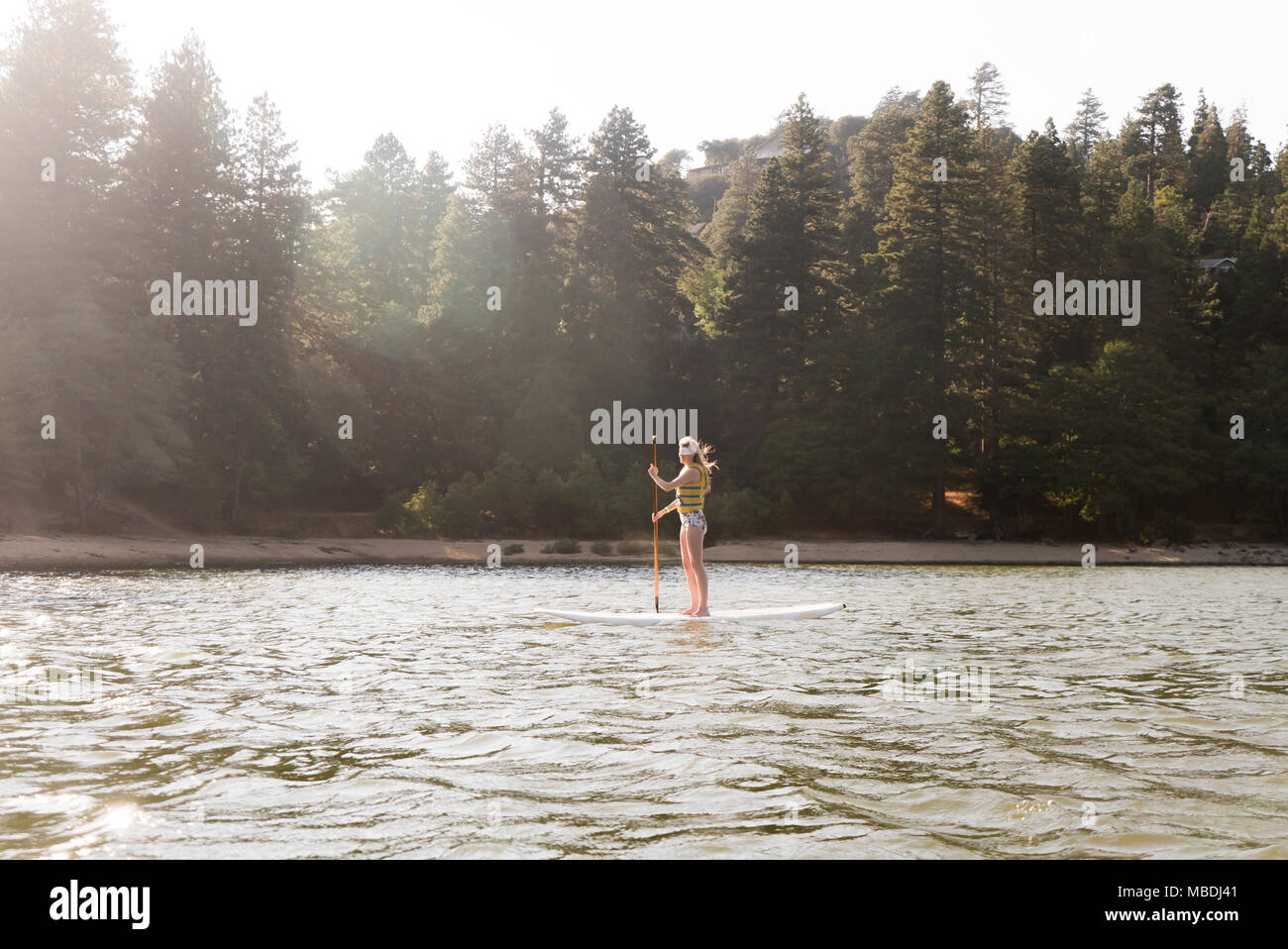 Woman paddleboarding on sunny, tranquil lake Stock Photo