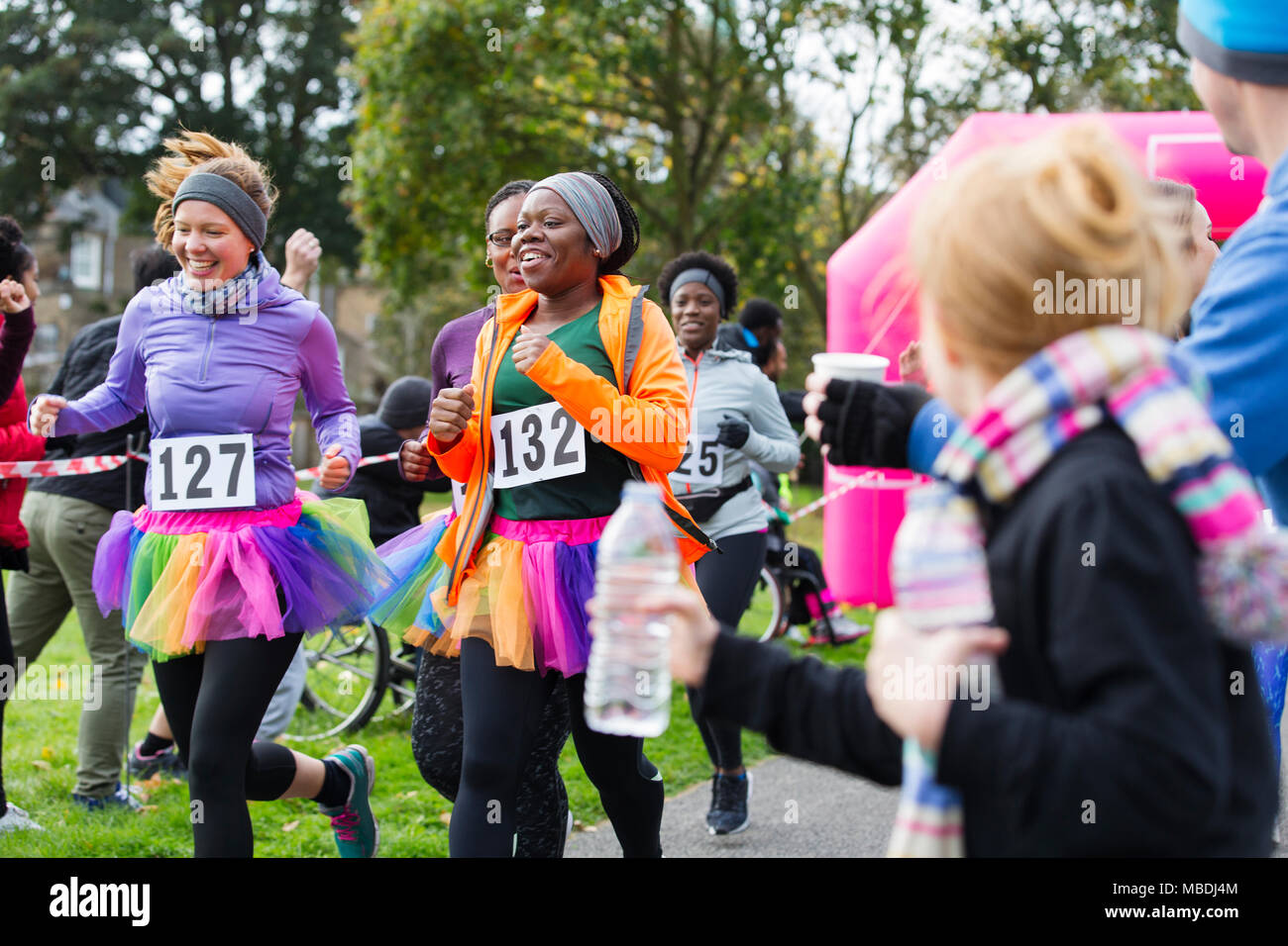 Female runners in tutus running at charity race in park Stock Photo