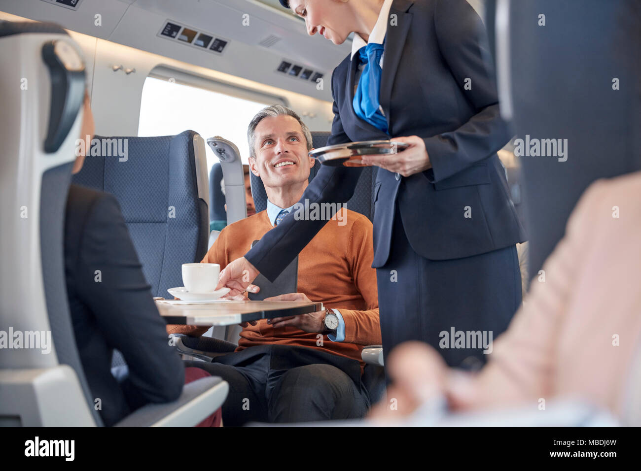 Attendant serving coffee to businessman on passenger train Stock Photo