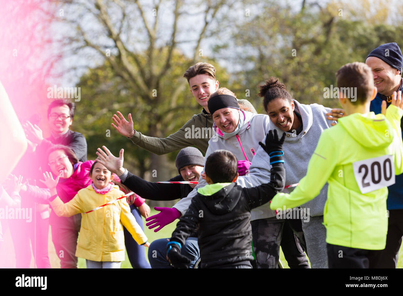 Spectators high-fiving runners at charity run in park Stock Photo