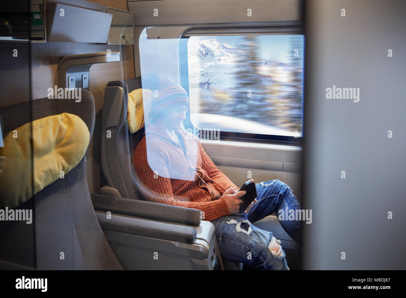 Young man using smart phone on passenger train Stock Photo
