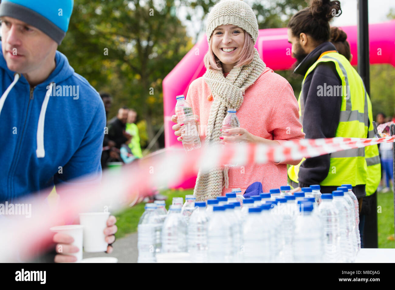 Portrait smiling female volunteer handing out water at charity run Stock Photo