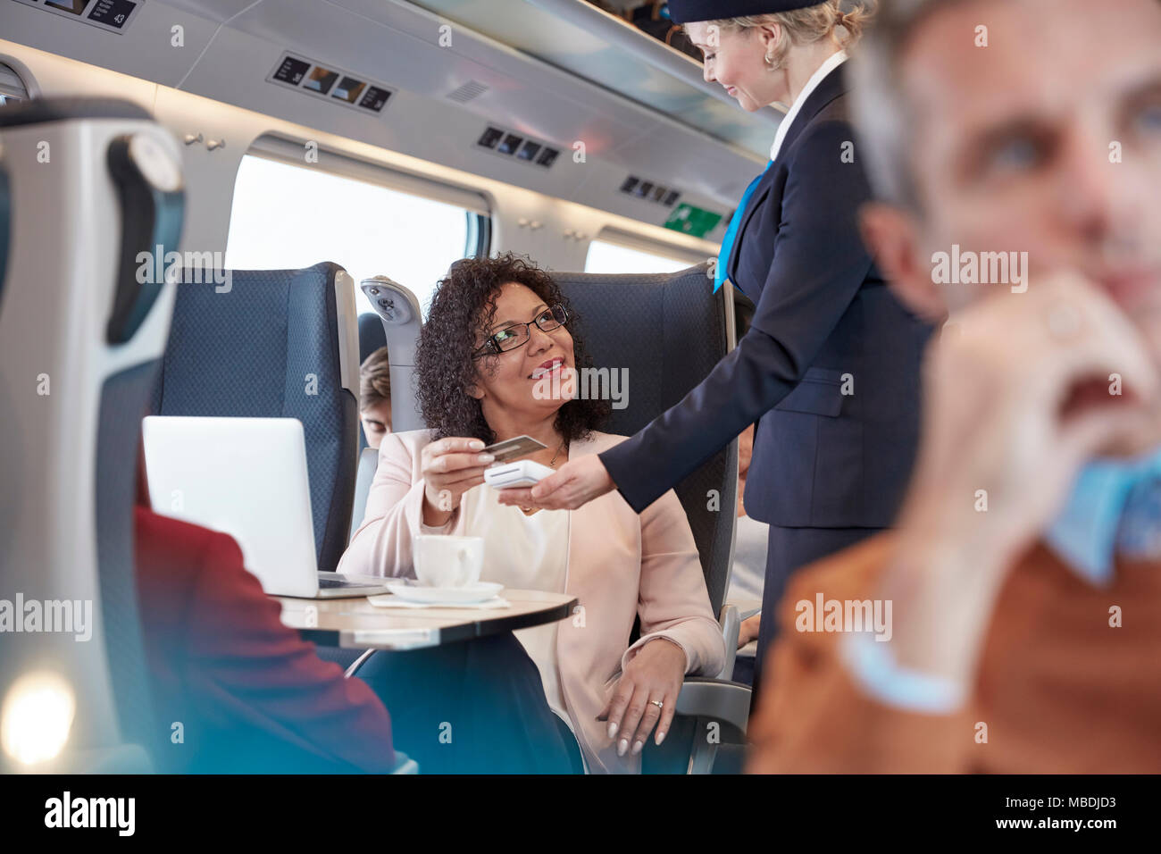 Woman with credit card using contactless payment, paying attendant on passenger train Stock Photo