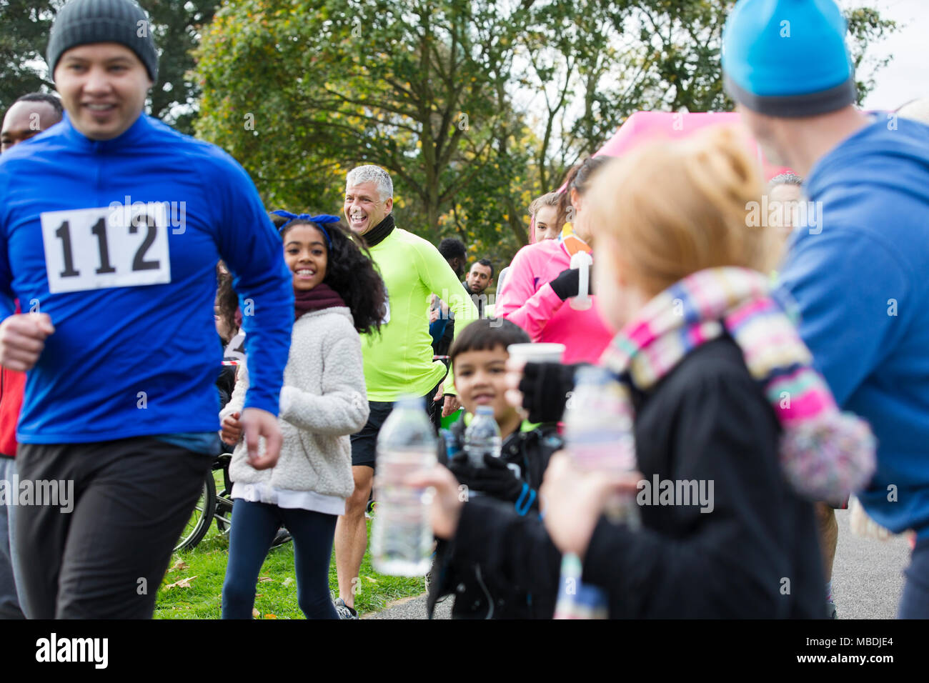 Spectators offering water to runners at charity run in park Stock Photo