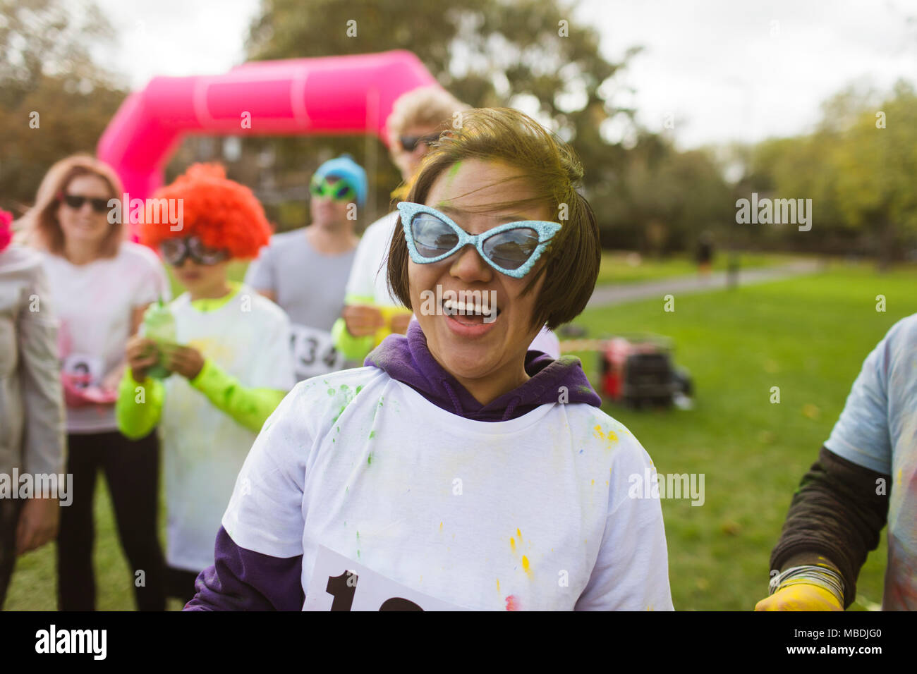 Portrait playful female runner in silly sunglasses at charity run in park Stock Photo