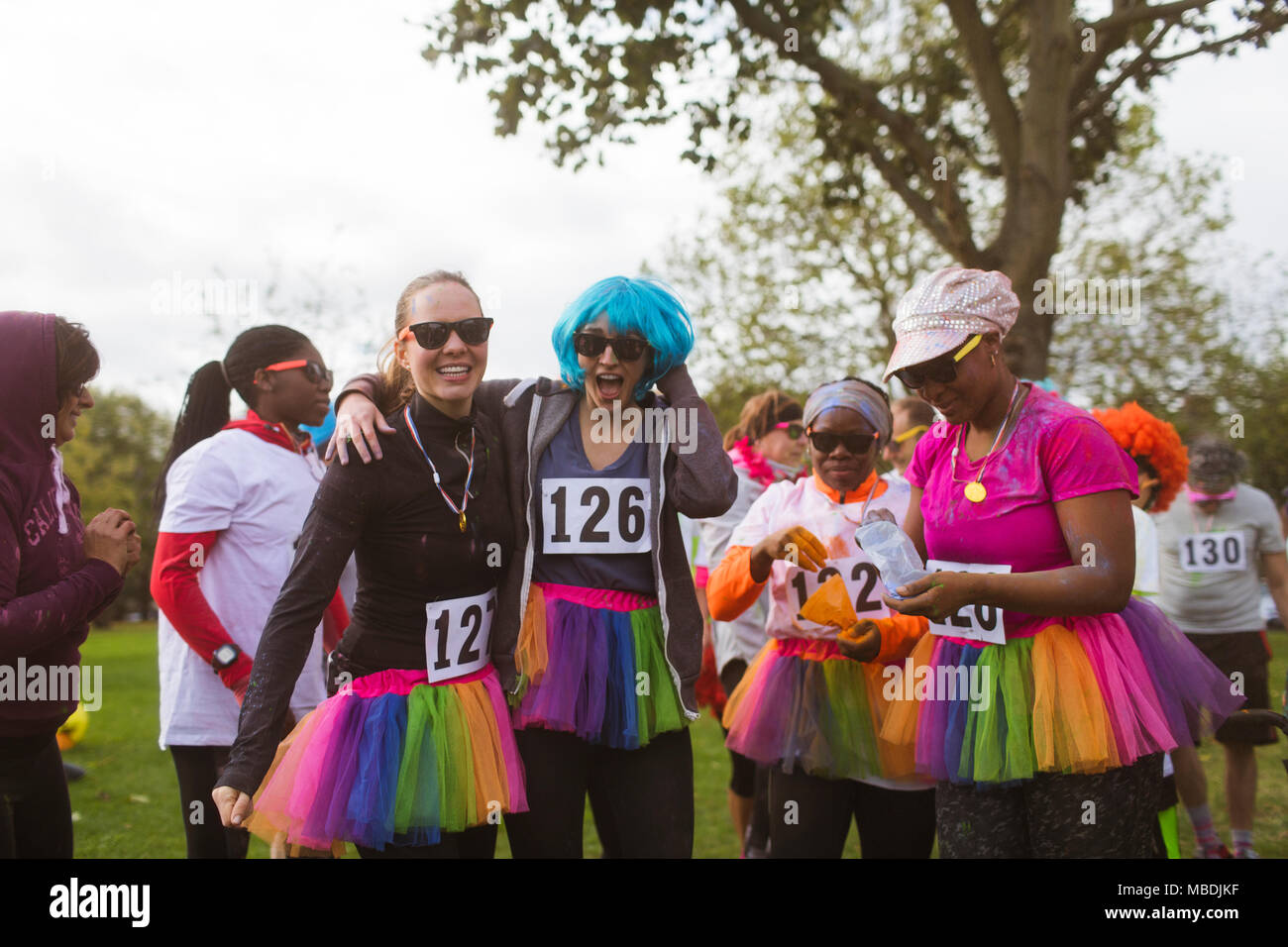 Portrait playful female runners in wigs and tutus at charity run in park Stock Photo
