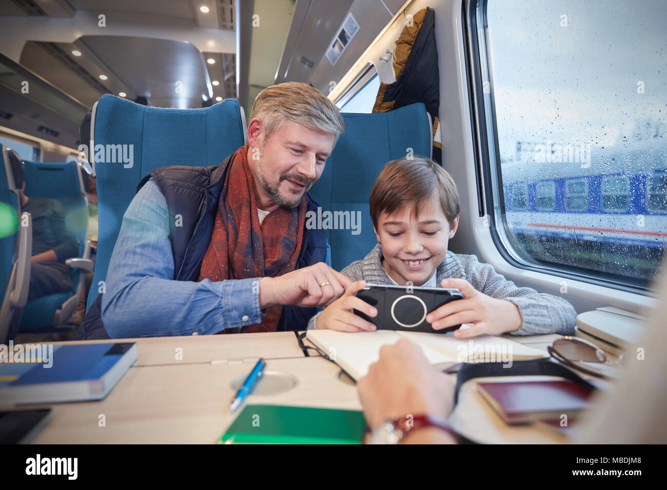 Father and son using smart phone on passenger train Stock Photo