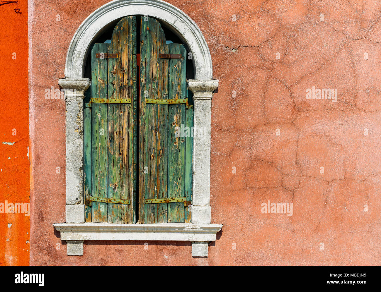 Looking up at an old stucco window frame bathed in light, with white window frames, in Venice, Italy. Stock Photo