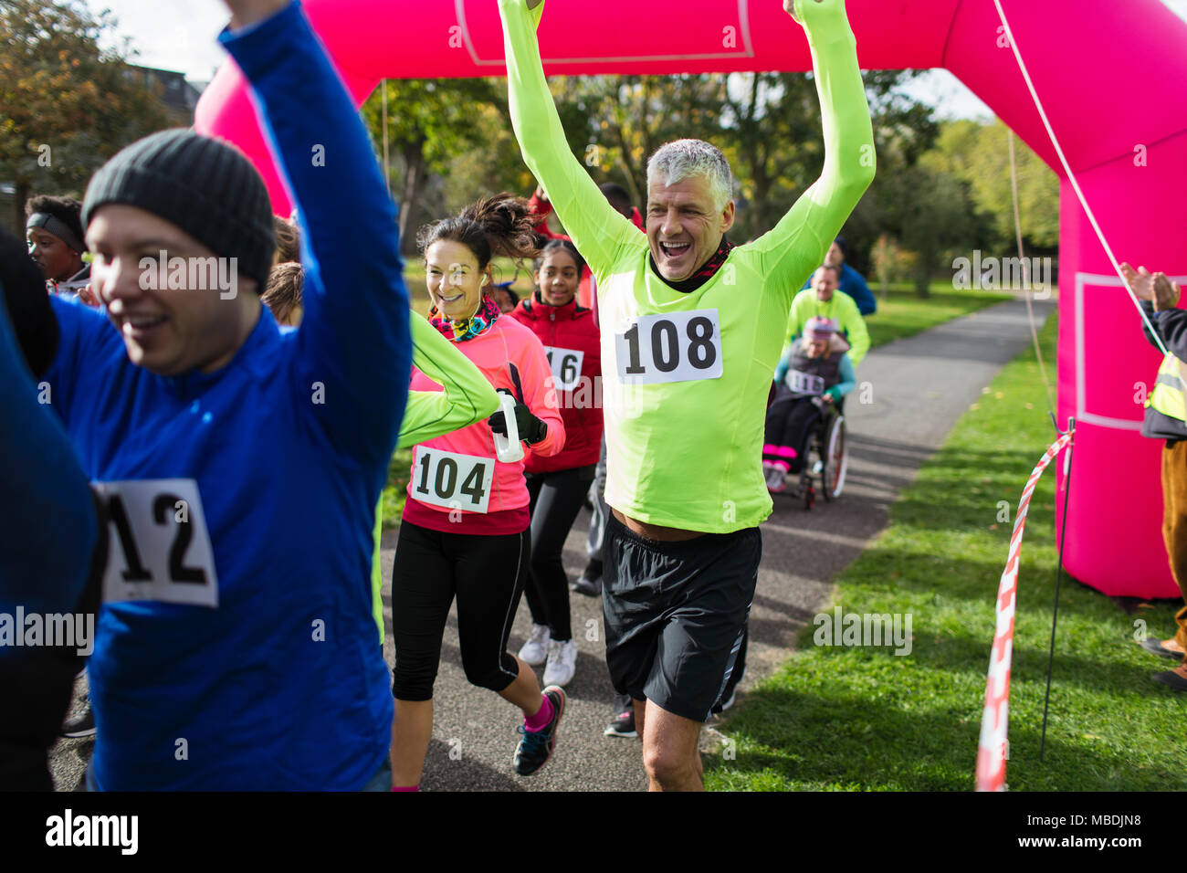 Enthusiastic runners cheering, crossing charity run finish line Stock Photo