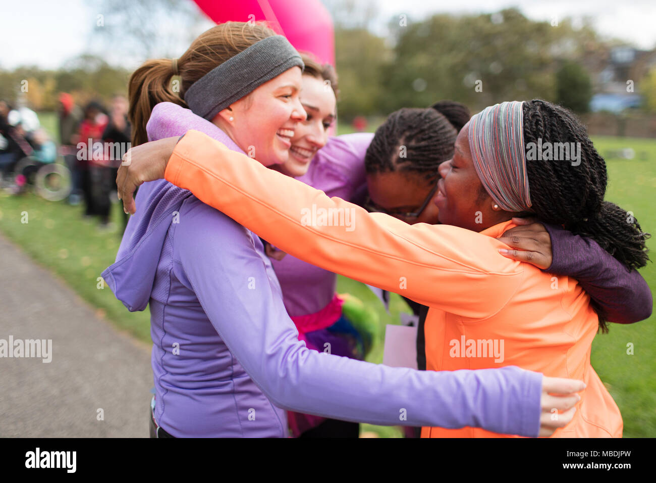 Happy female runners hugging at charity run finish line, celebrating Stock Photo