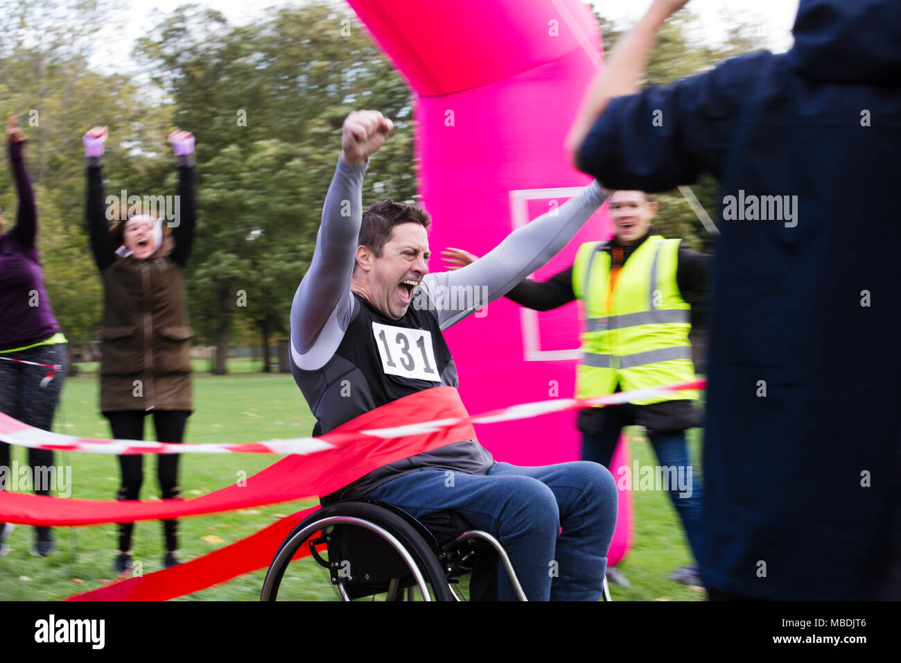 Enthusiastic man in wheelchair crossing charity race finish line Stock Photo