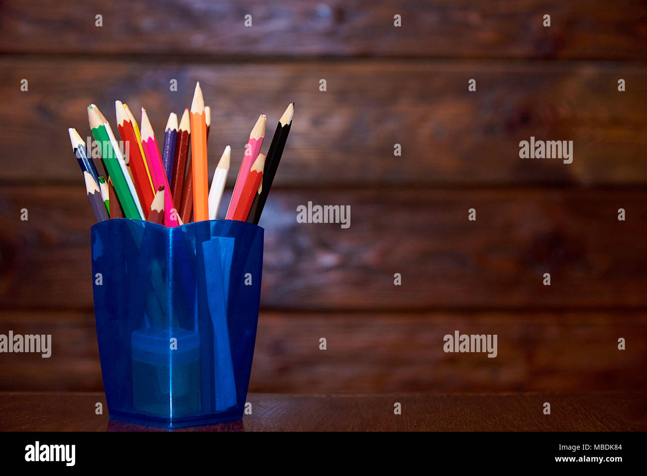 Colored pencils in blue a glass on a wooden background. Copy space Stock Photo