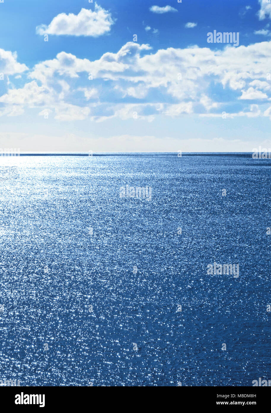 Sparkling sea or seascape background with glittering water and blue sky with fluffy clouds and copy space. Stock Photo