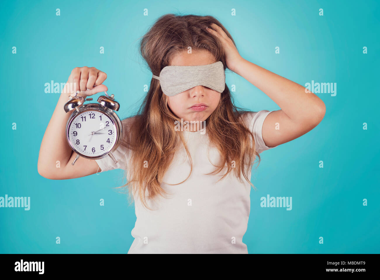 little girl with an alarm clock on blue background Stock Photo