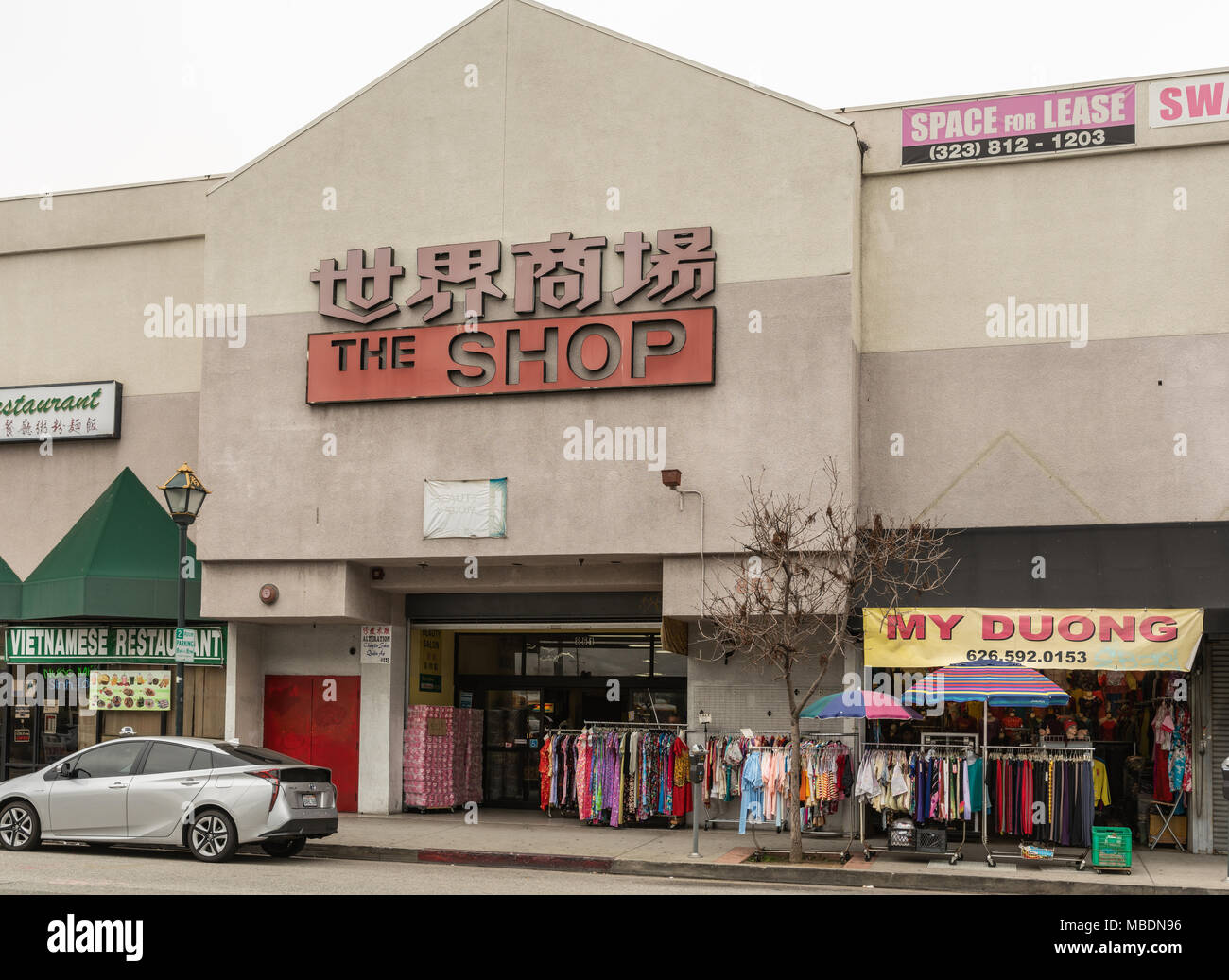 Los Angeles, CA, USA - April 5, 2018: Shopping mall along Broadway in Chinatown. Beige facade, colorful display of clothing, advertisements and street Stock Photo