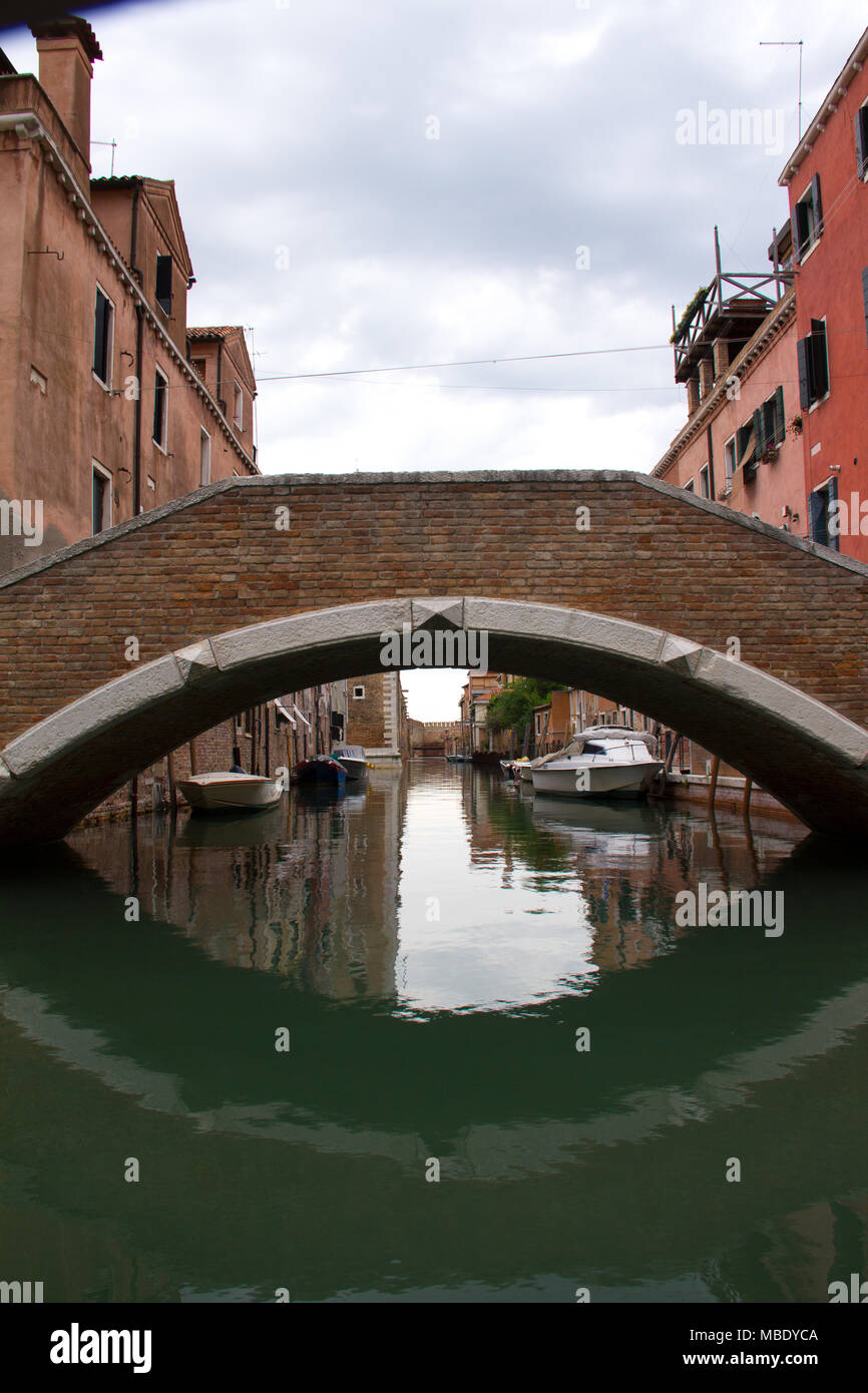 View under a bridge arch , mirrored on the water surface in Venice, Italy Stock Photo