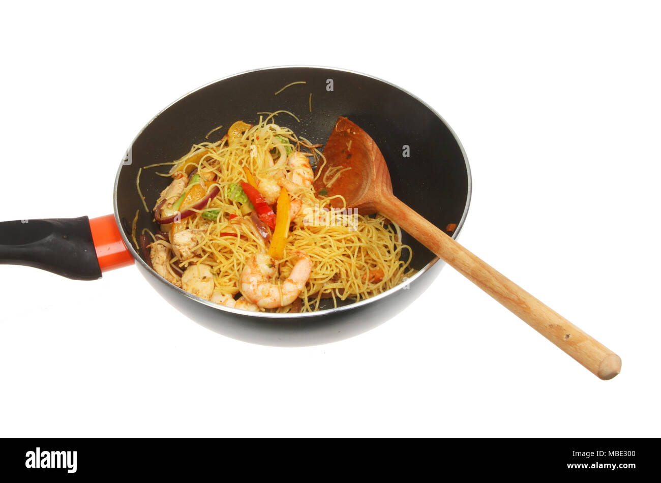 Singapore noodles prawns and stir fry vegetables in a wok with a wooden spoon isolated against white Stock Photo