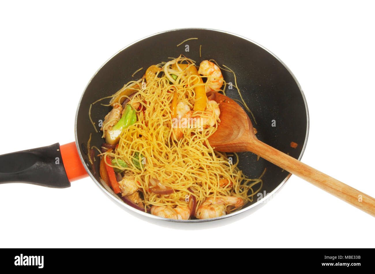 Noodle, chicken and prawn stir fry in a wok with a wooden spoon isolated against white Stock Photo