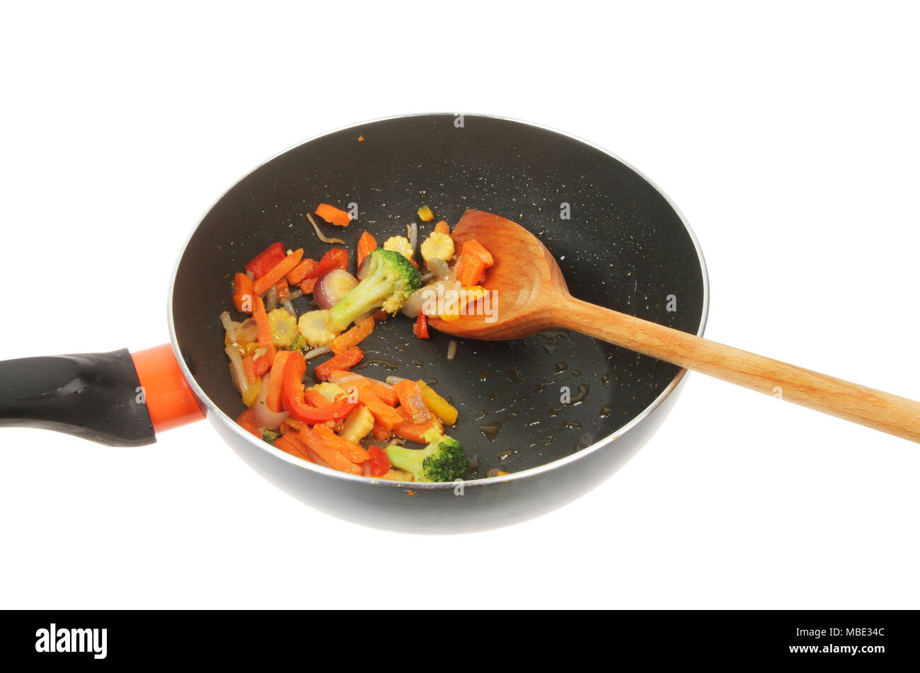 Stir fried vegetables with a wooden spoon in a wok isolated against white Stock Photo