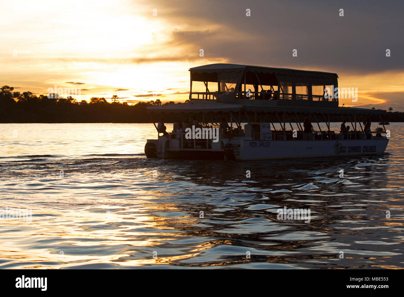A boat during a sunset cruise on the Zambezi River near Victoria Falls in Zimbabwe. The sunset cruises provide a means of viewing wildlife and birds. Stock Photo