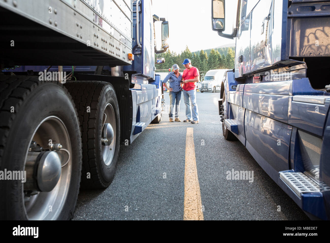 https://c8.alamy.com/comp/MBEDE7/caucasian-man-and-woman-truck-driving-team-going-over-data-on-a-cell-phone-while-standing-between-trucks-at-a-truck-stop-MBEDE7.jpg