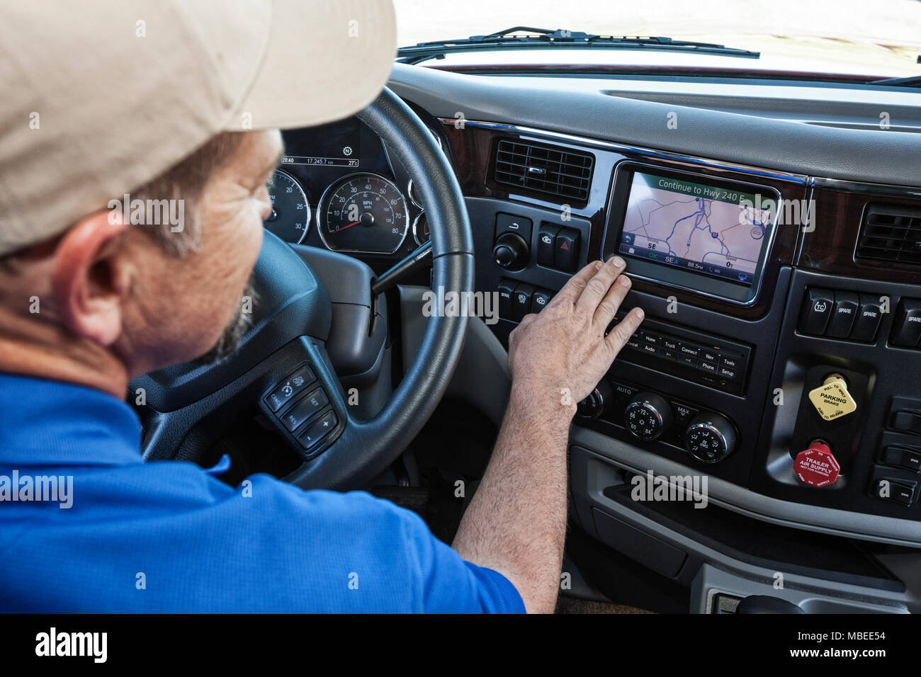 Driver parked by the side of the road using a GPS mapping device in the cab of a  commercial truck. Stock Photo
