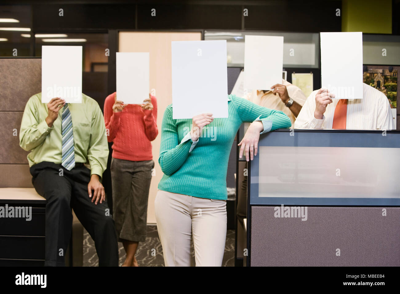 Team of business people standing with blank pieces of paper in front of their faces. Stock Photo
