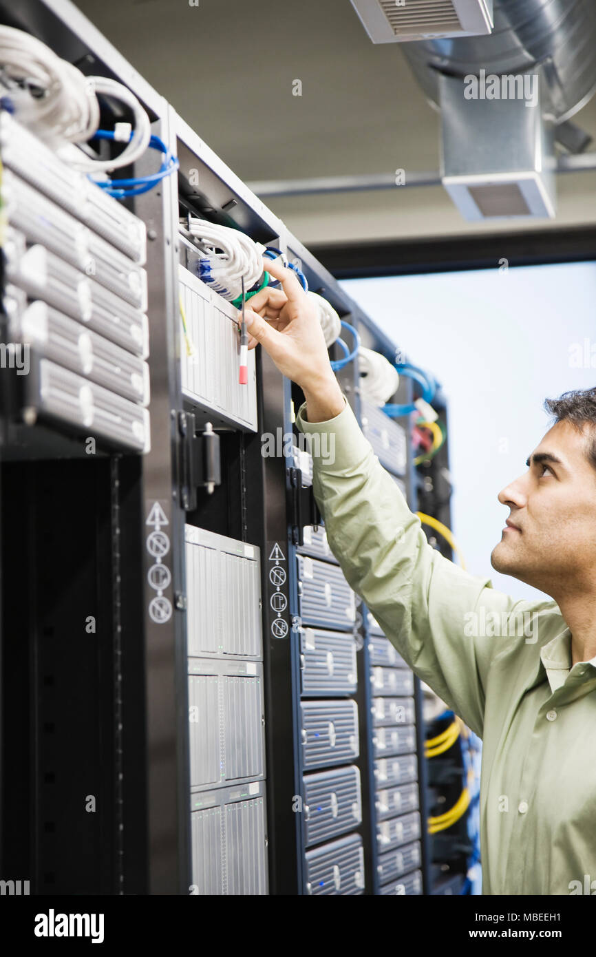 Male computer technician working on servers in a computer server farm. Stock Photo
