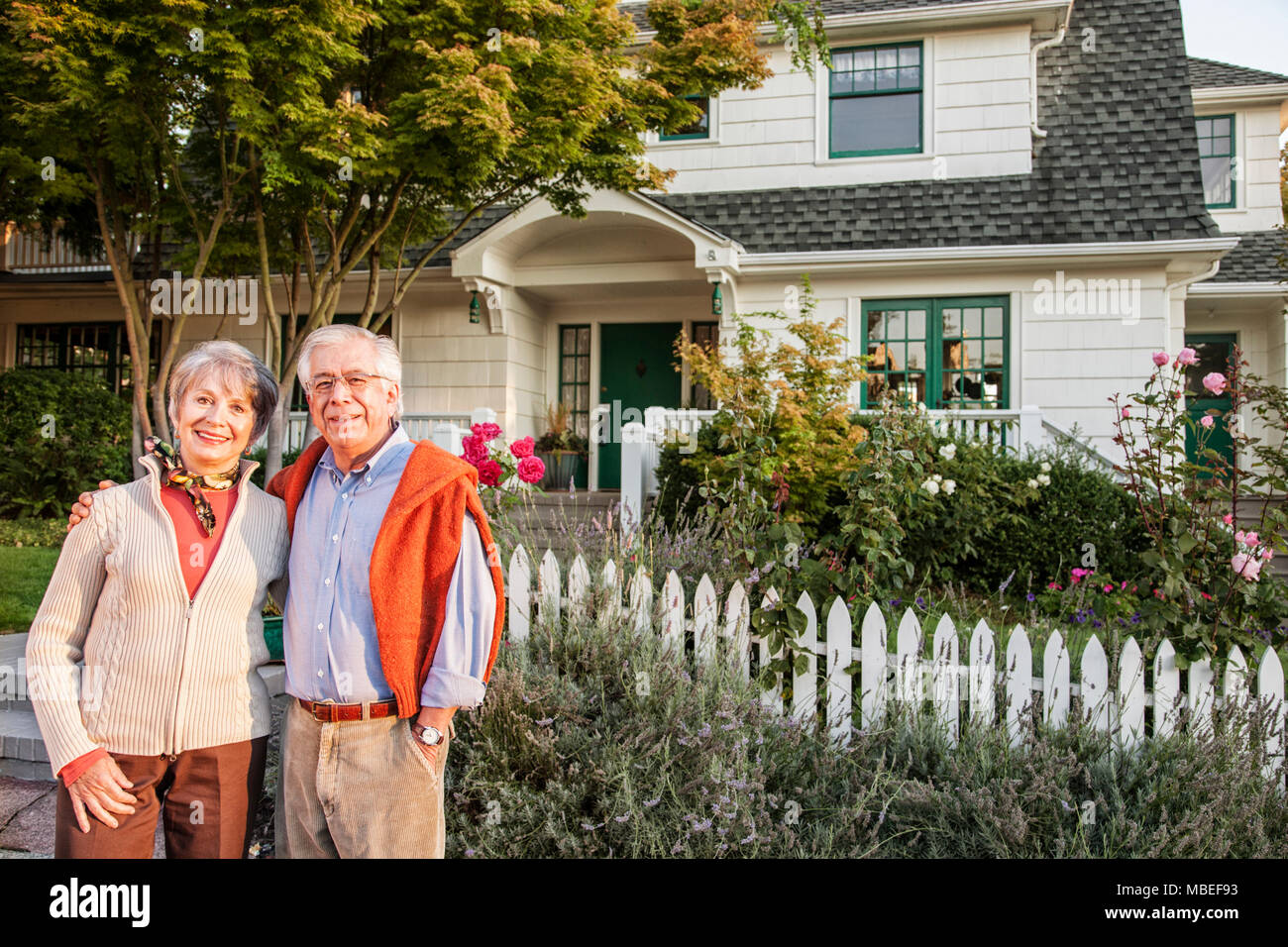 Hispanic senior couple in front of their remodeled older style home ...