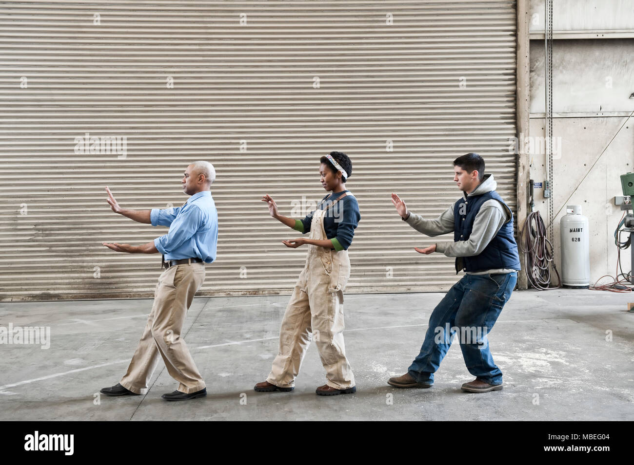 Mixed race group of workers and a black man management peson taking a break on the floor of a factory. Stock Photo
