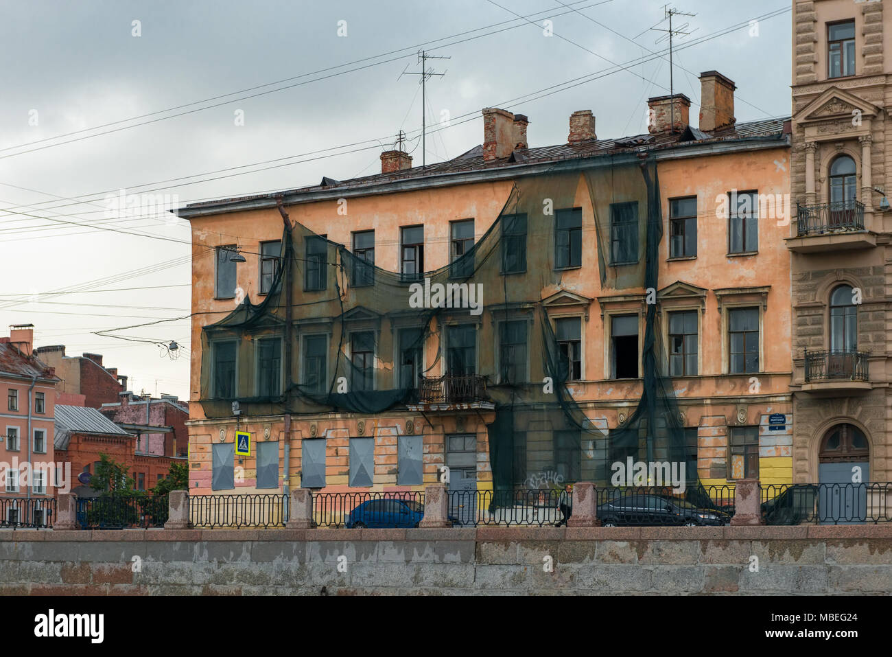 RUSSIA, SAINT PETERSBURG - AUGUST 18, 2017: Kryukov Canal embankment, 28. Old house covered green building facade mesh. Preparations for the renovatio Stock Photo