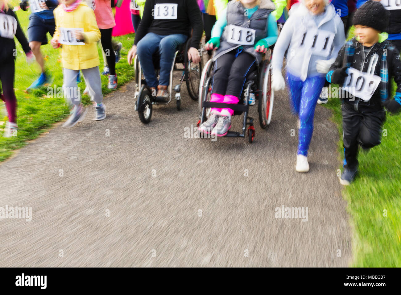 People in wheelchairs and runners moving at charity race Stock Photo