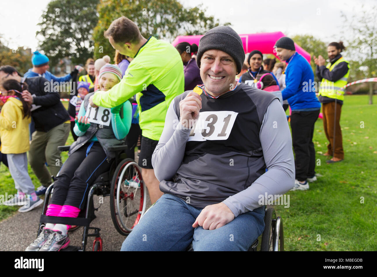 Portrait smiling, confident man in wheelchair showing medal at charity race in park Stock Photo