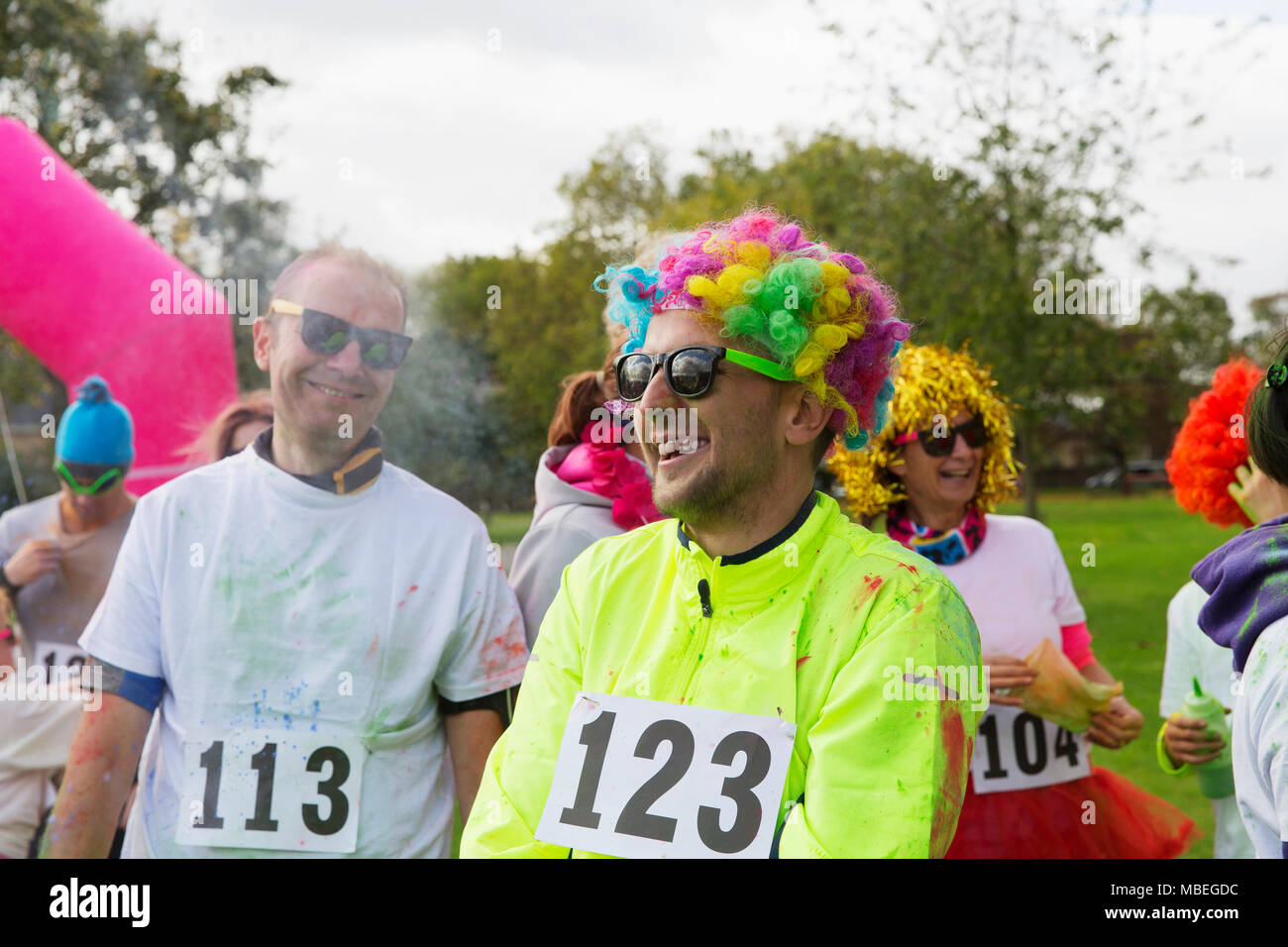 Playful runner in wig at charity run in park Stock Photo