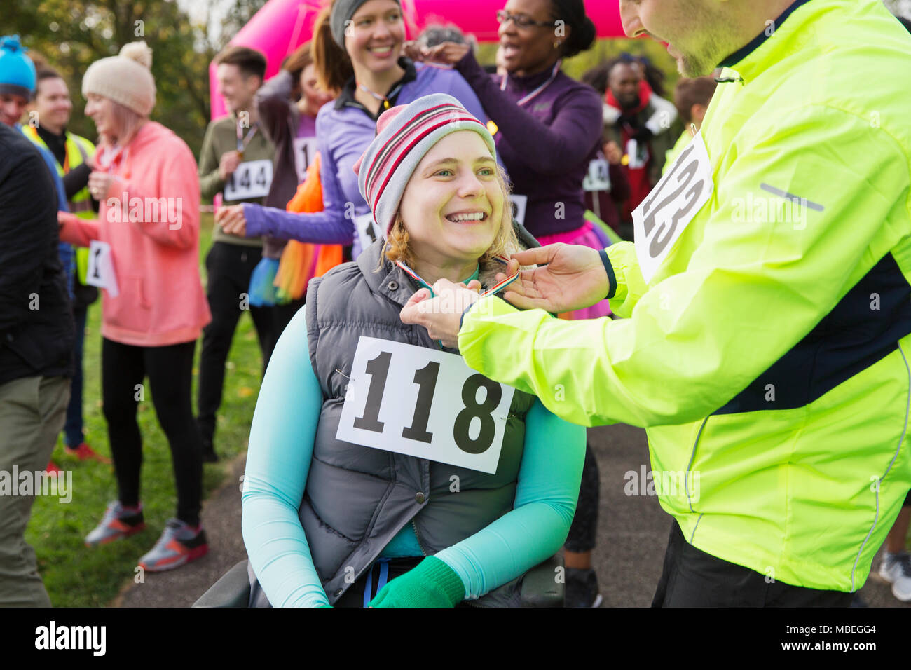 Man placing medal around neck of woman in wheelchair at charity race Stock Photo