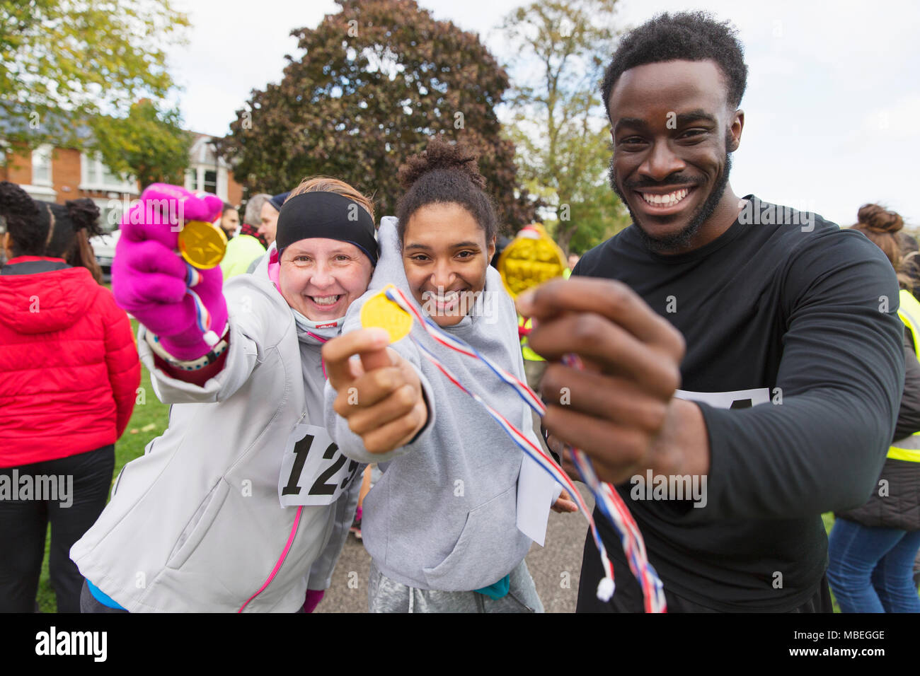 Portrait enthusiastic runners showing medals at charity run in park Stock Photo