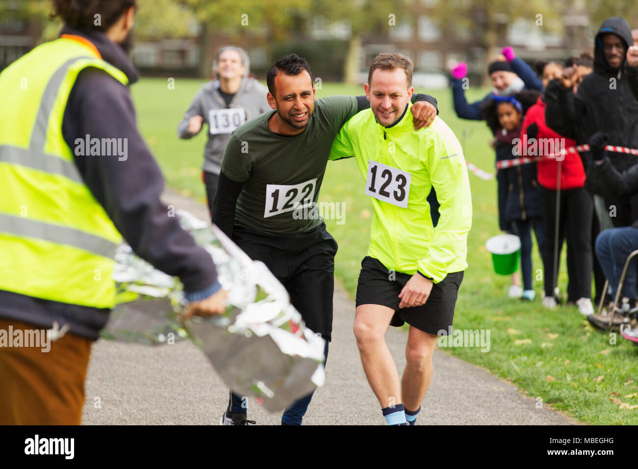 Runner helping injured man running at marathon Stock Photo