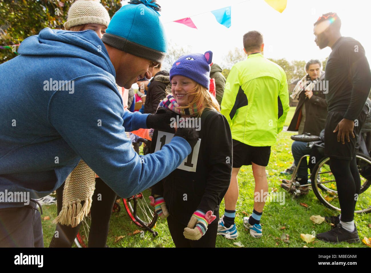 Father pinning marathon bib on daughter at charity run in park Stock Photo