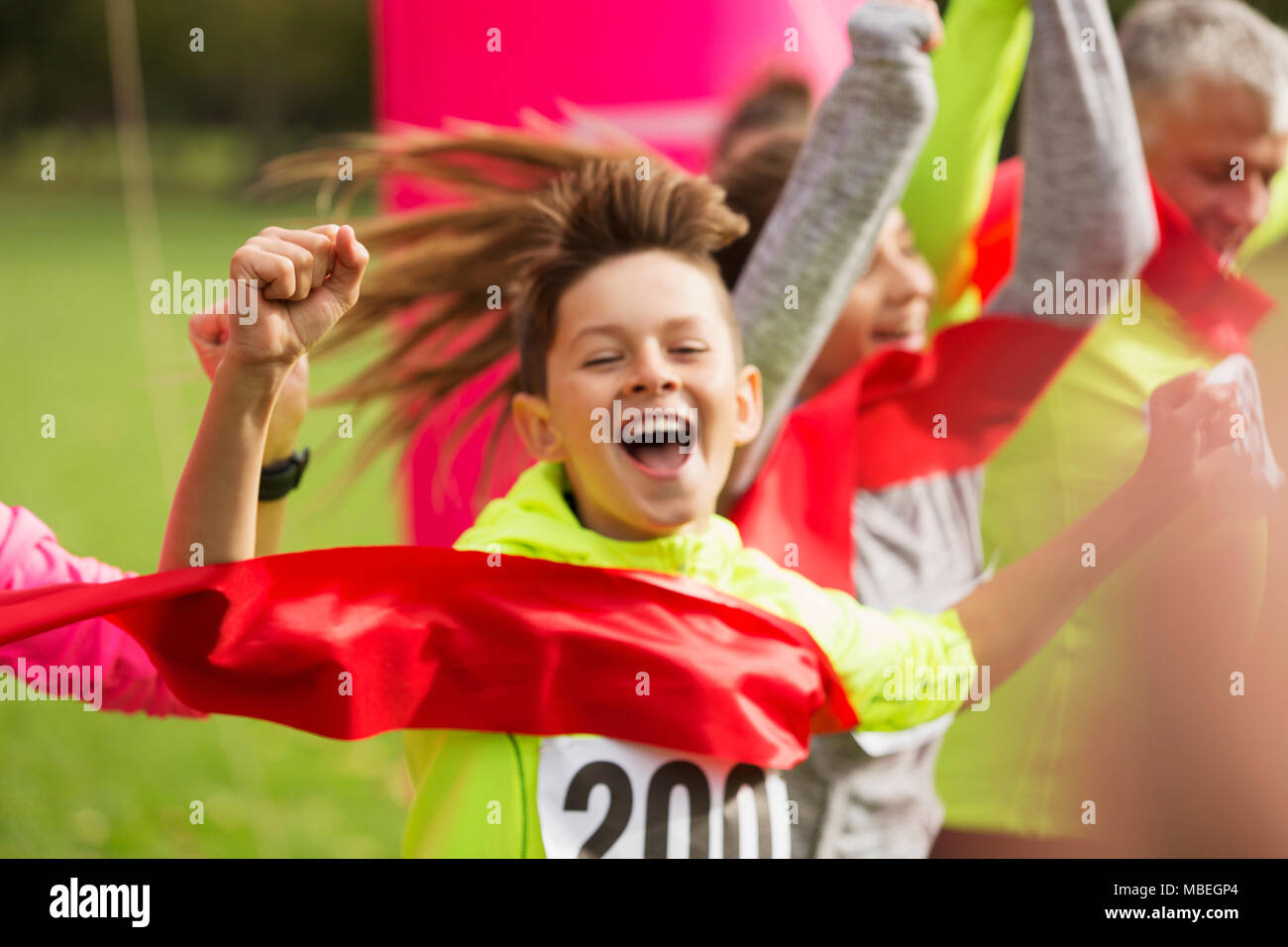 Enthusiastic boy runner crossing charity run finish line Stock Photo