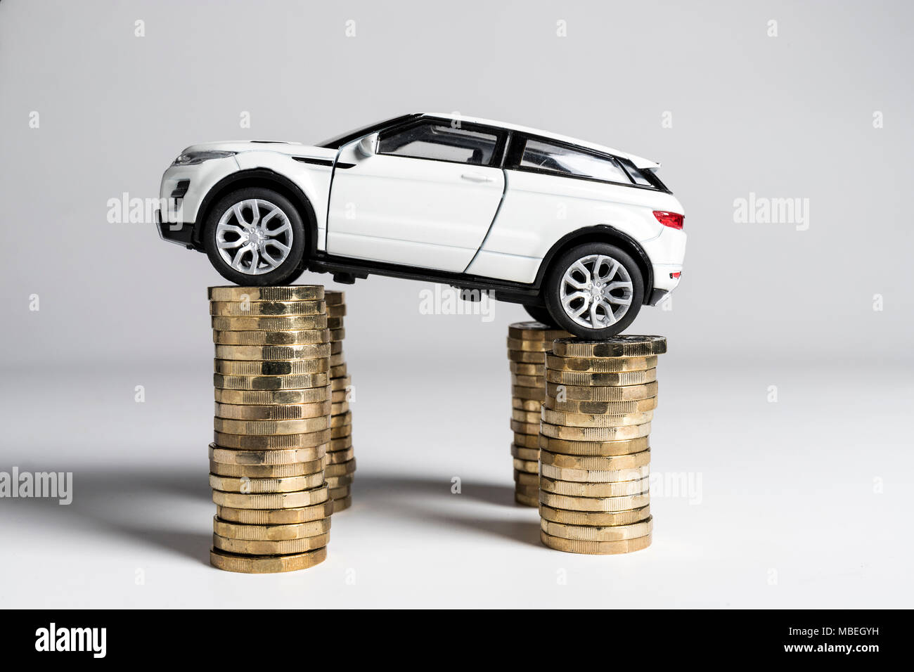 A toy Land Rover Evoque balanced on piles of £1 coins. Stock Photo