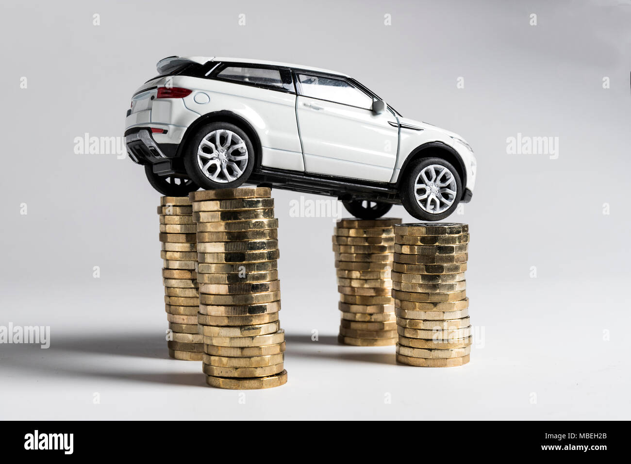 A toy Land Rover Evoque balanced on piles of £1 coins. Stock Photo