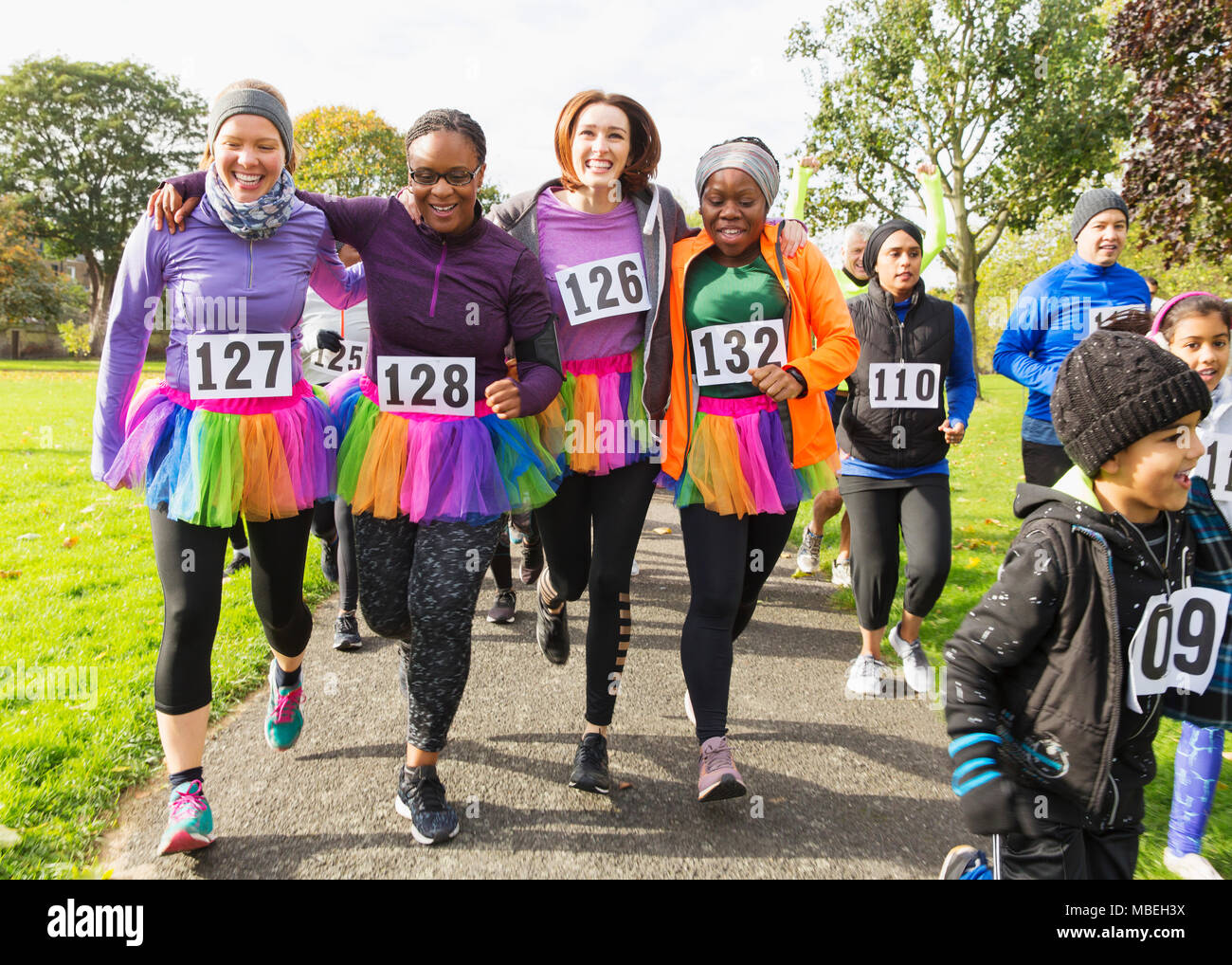 Smiling female runners in tutus walking at charity run in park Stock Photo