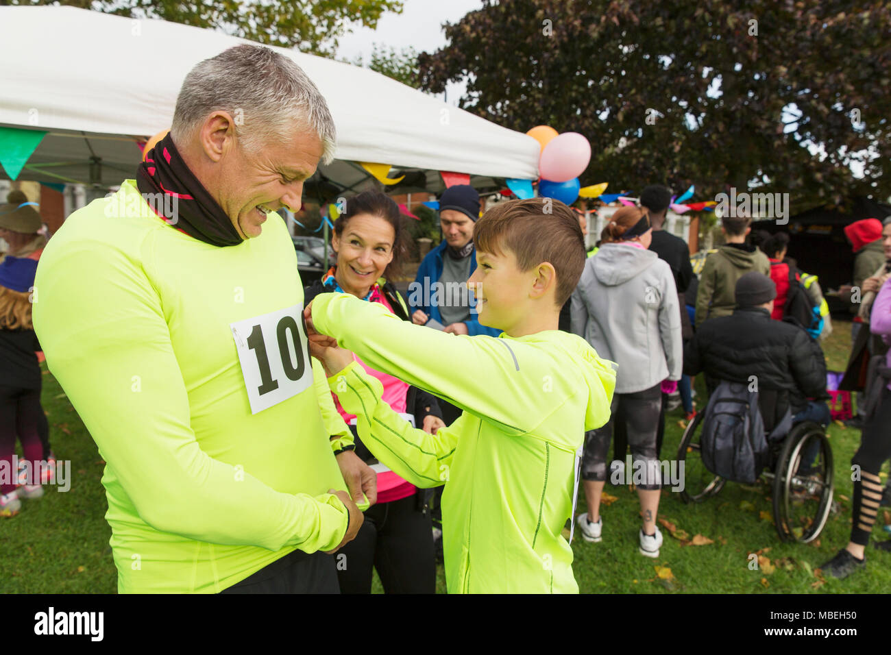 Family runners pinning marathon bibs, preparing for charity run in park Stock Photo