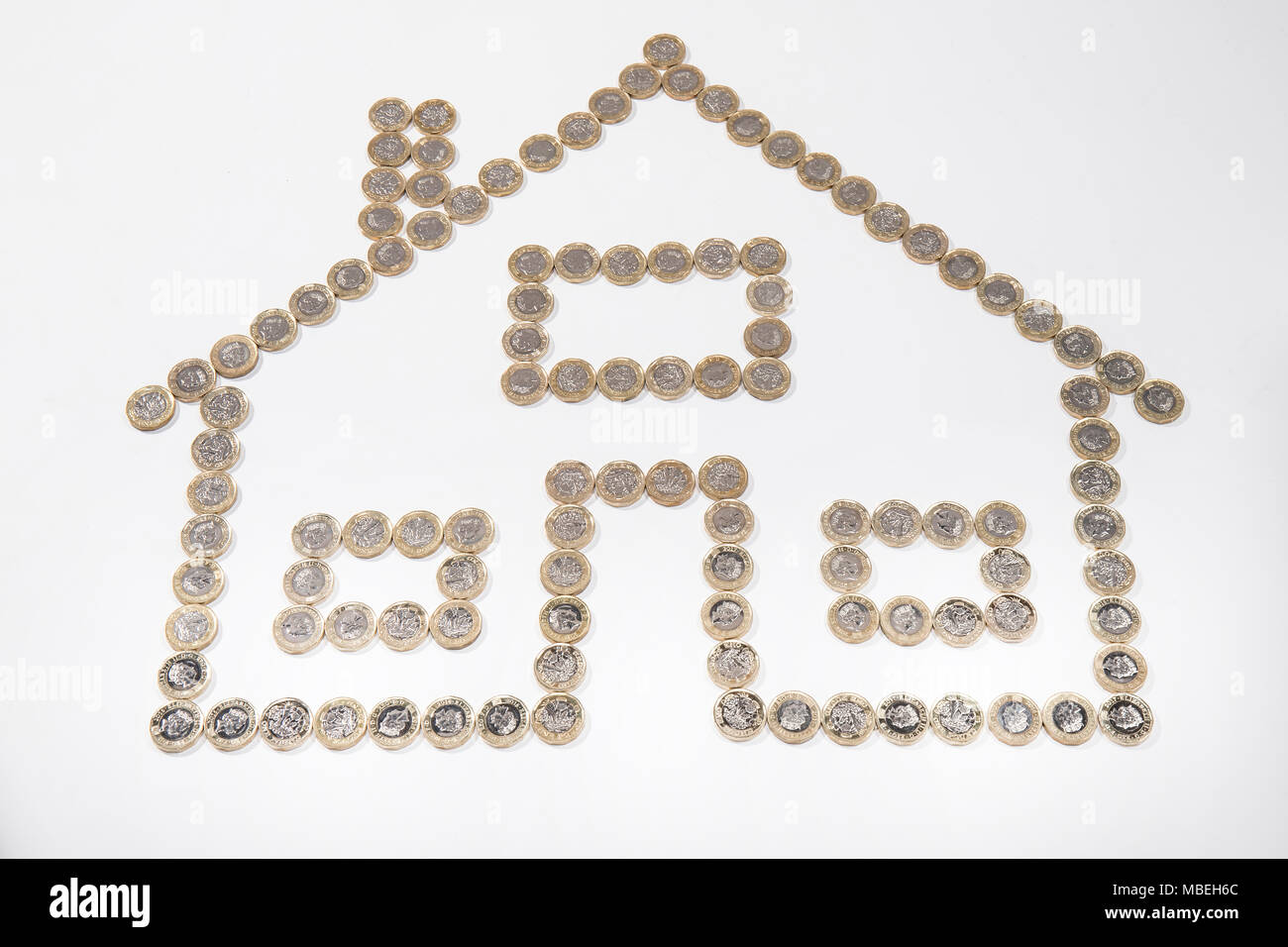 UK £ coins laid out in the shape of a house with 3 windows Stock Photo
